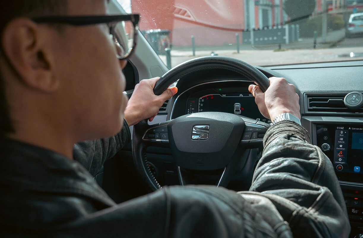 Leerling achter het stuur van een SEAT lesauto van Rijschool Caland tijdens de examenrit in Amsterdam.