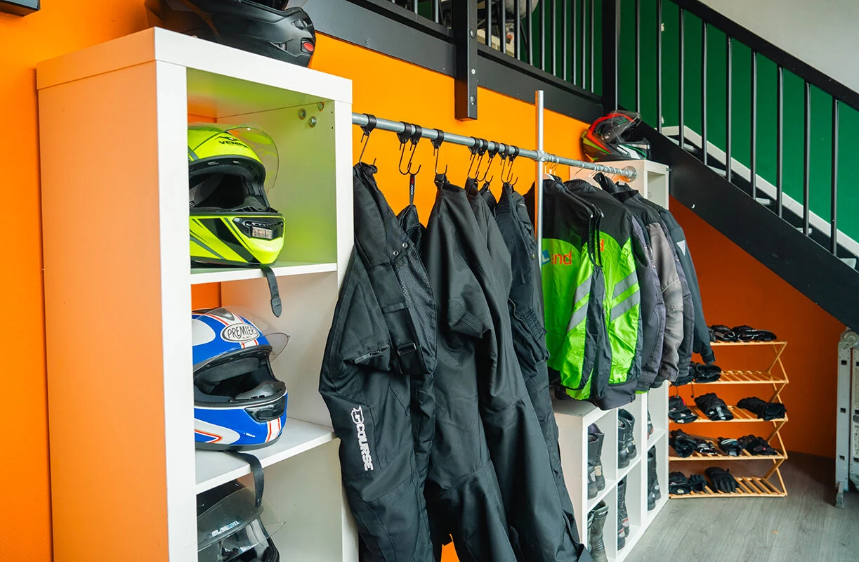 Een overzicht van de beschikbare motoruitrusting bij Rijschool Caland Amsterdam, waaronder helmen, motorjassen, handschoenen en schoenen voor leerlingen tijdens de proefles motorrijden.