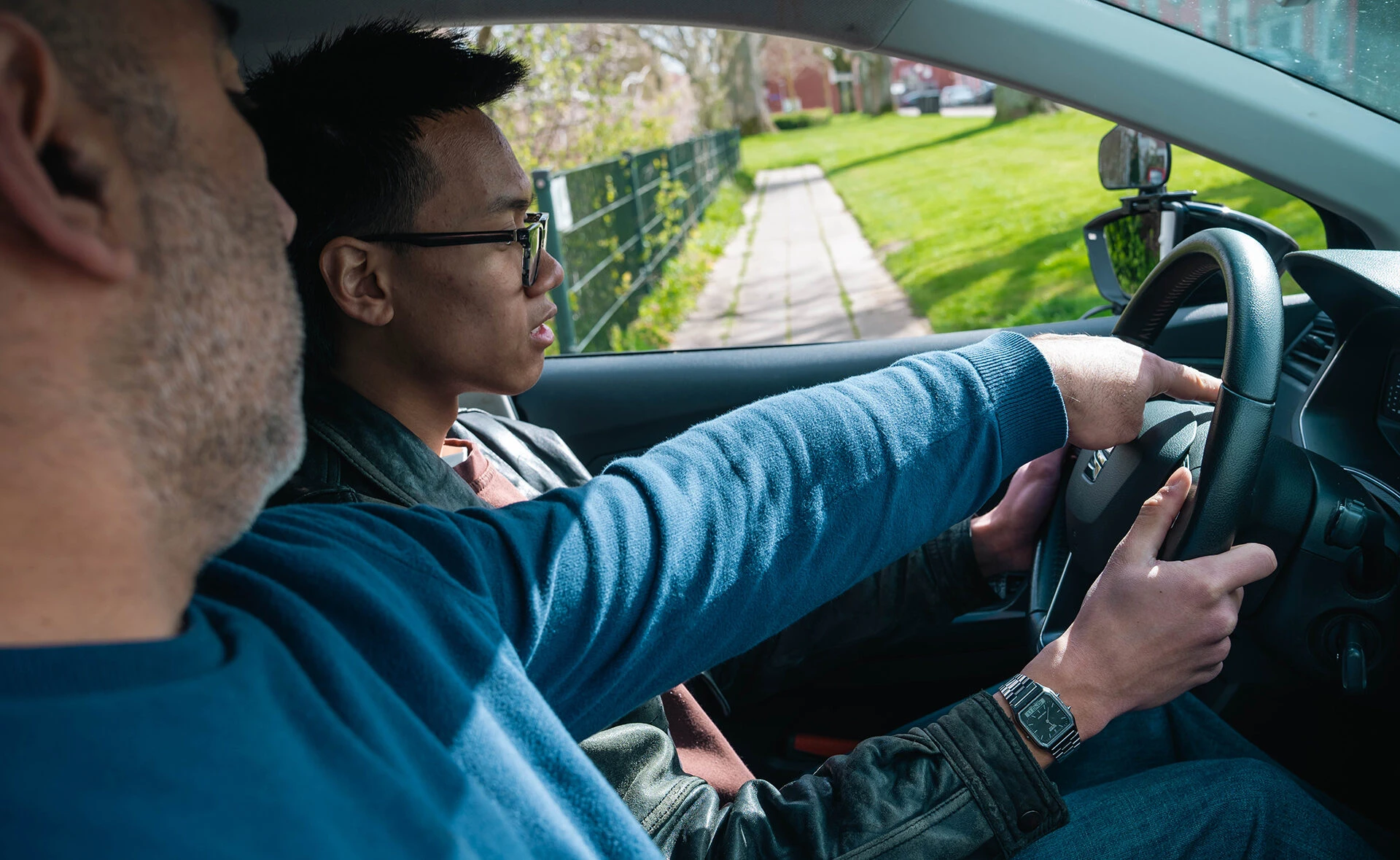 Leerling krijgt uitleg van een rijinstructeur terwijl hij achter het stuur zit tijdens een rijles bij Rijschool Caland in Amsterdam, met aandacht voor verkeersinzicht en voertuigbediening.