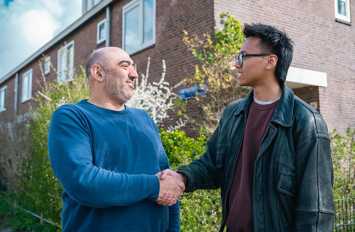 Een instructeur van Rijschool Caland geeft een leerling een hand na afloop van de tussentijdse toets, als onderdeel van de persoonlijke nabespreking en feedback.